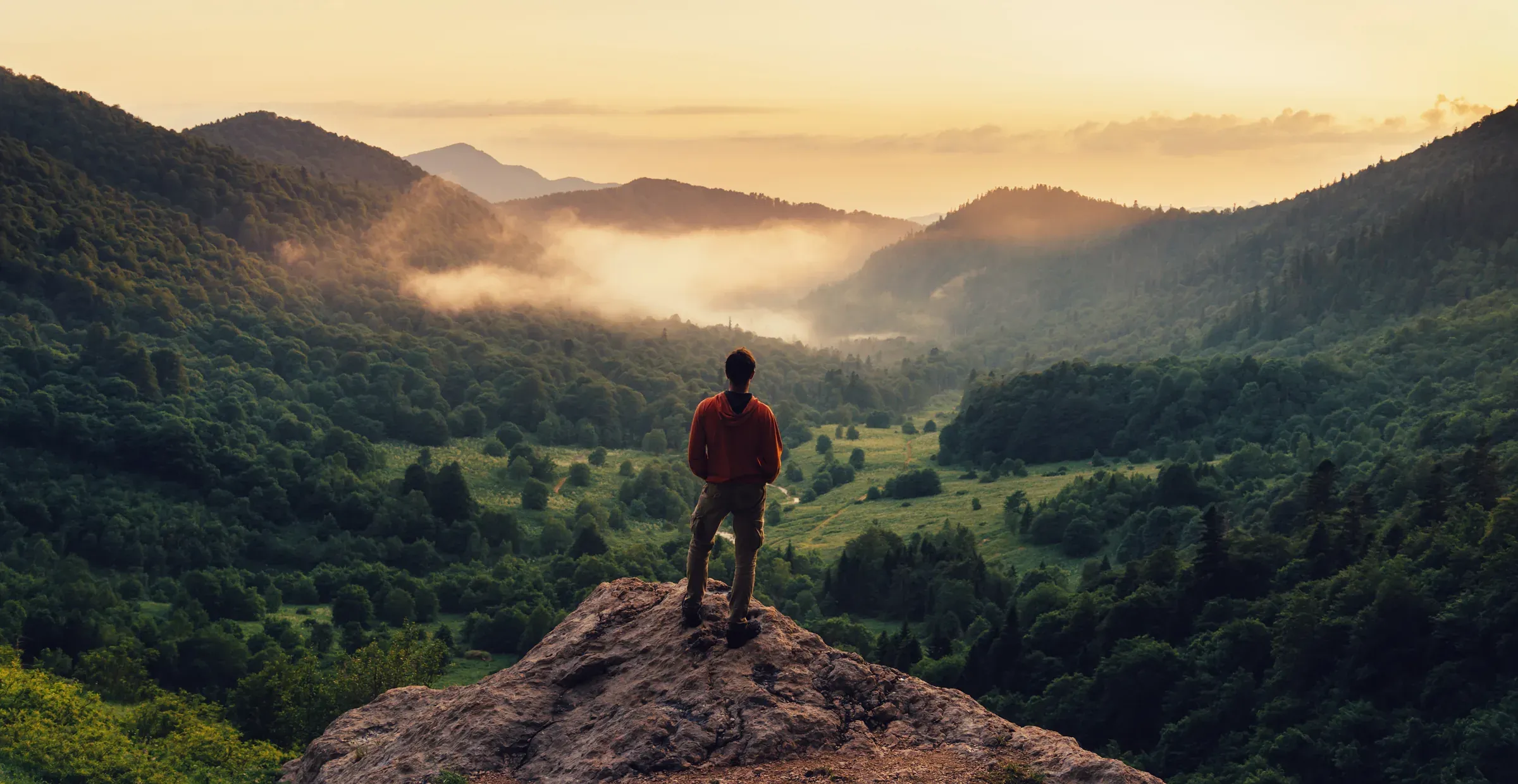 A person taking in a mountain valley at sunrise, representing peace of mind