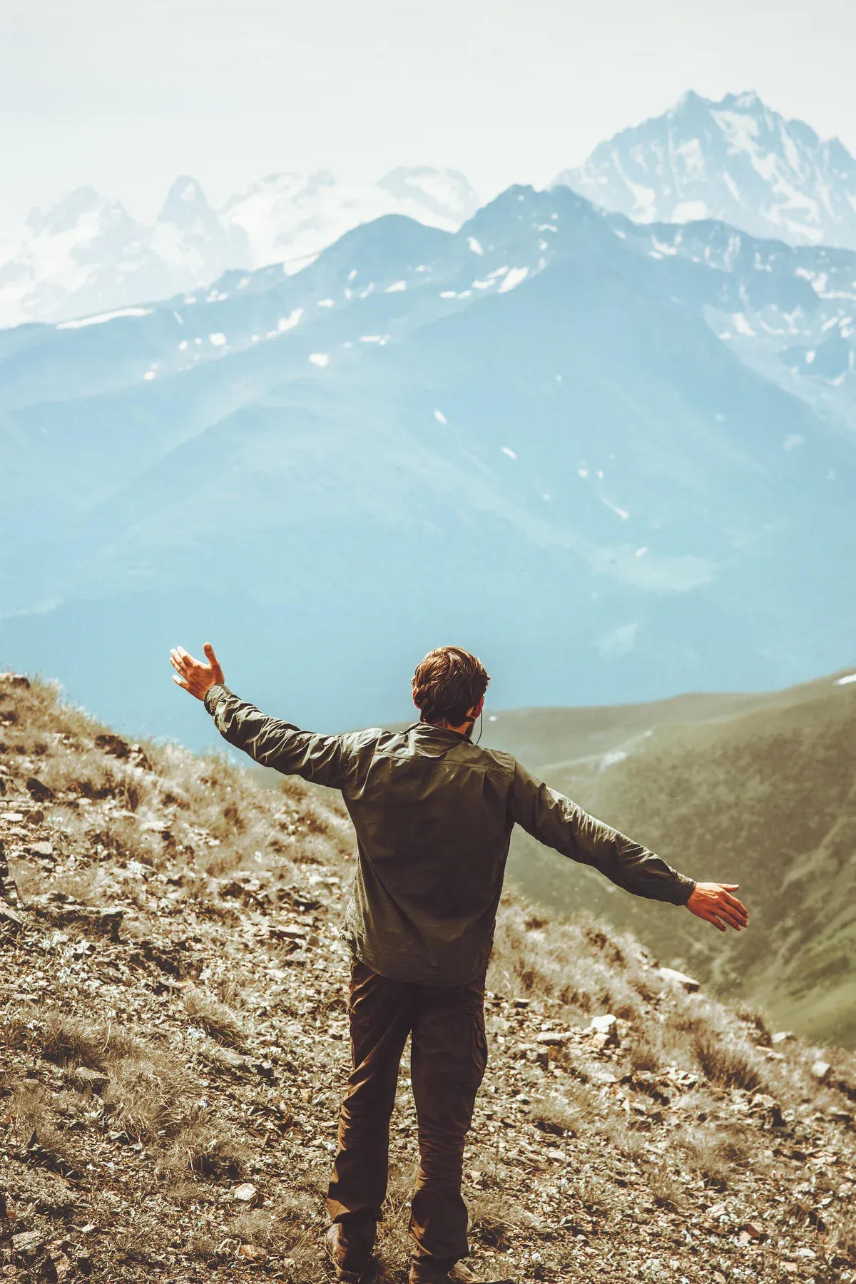 A person standing on a summit with arms raised, celebrating